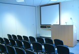 Classroom with chairs, blackboard and small stage with microphones