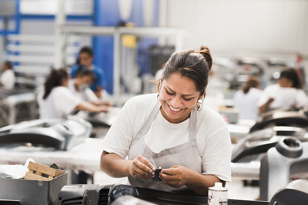 a factory worker smiling as she works