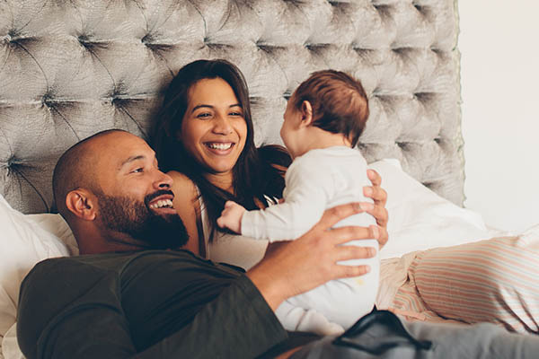 Father, Mother, and baby smiling in bed : Photo