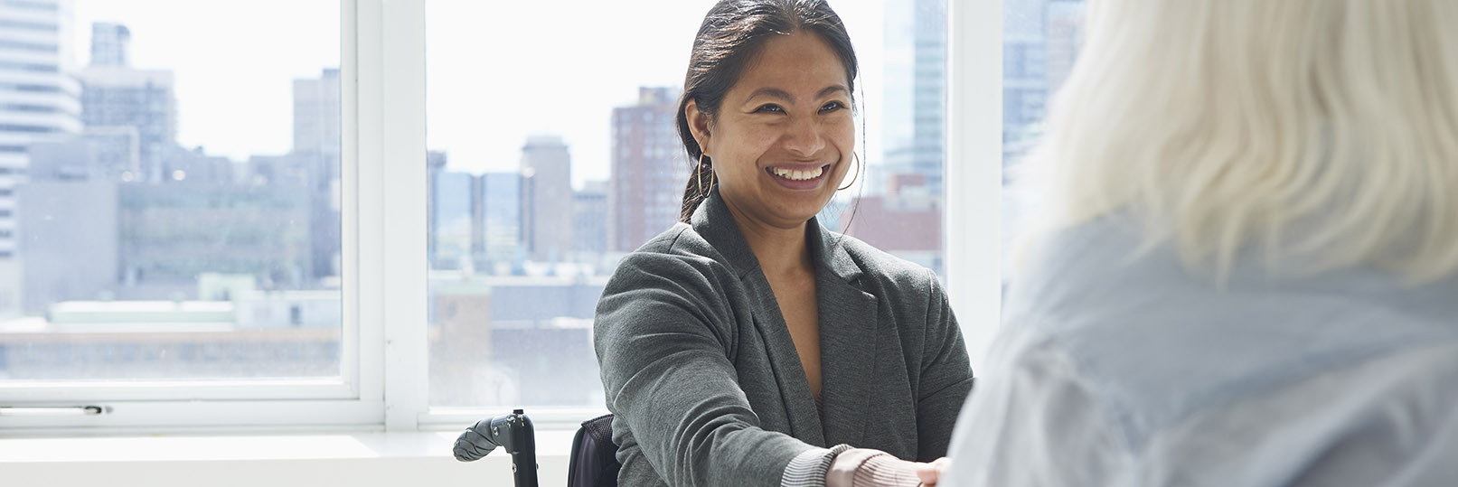 a woman in a wheelchair extending her hand at a job interview