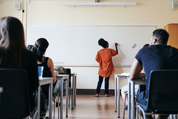 a classroom of adult learners and their teacher who is facing a whiteboard