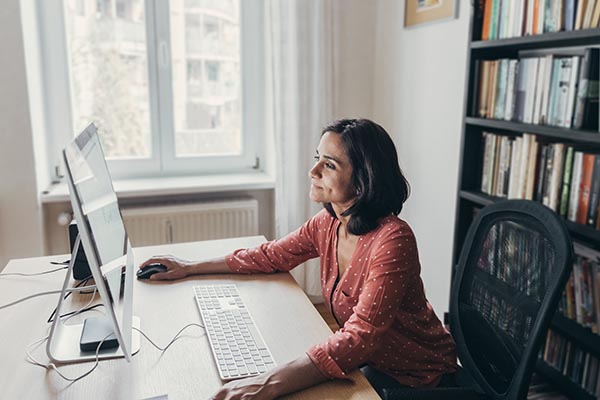 a woman working at a computer at a desk in her home