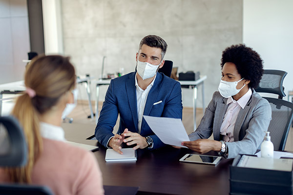 two people talking to a candidate at a job fair, all wearing face masks