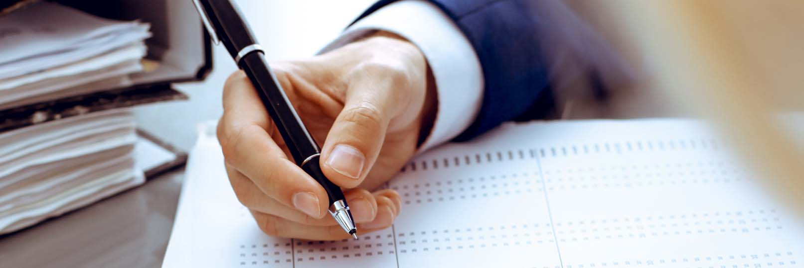 man looking at a sheet of numbers and holding a pen