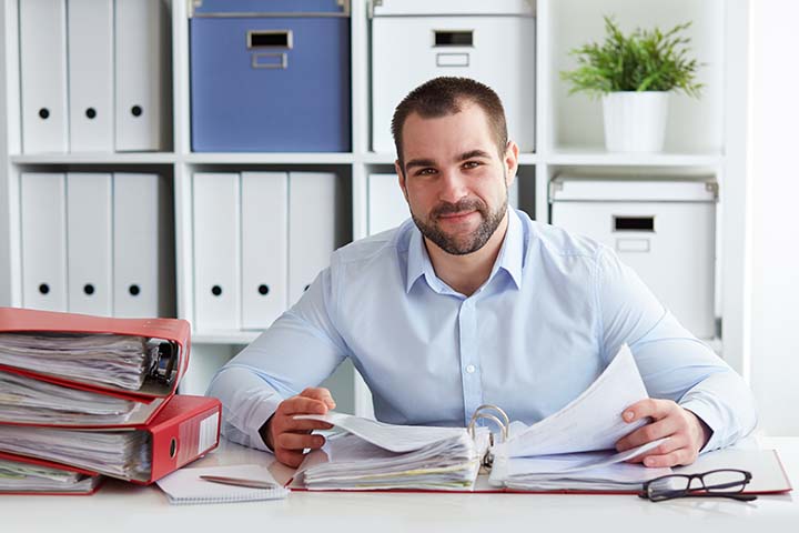 man at a desk with binders and papers