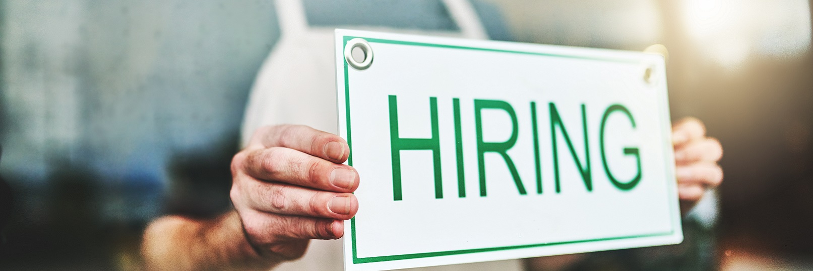 Store owner hanging hiring sign in shop window