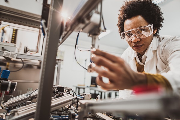 Lab worker examining machine part in lab