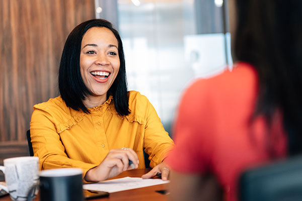 Woman sitting across desk from other woman.