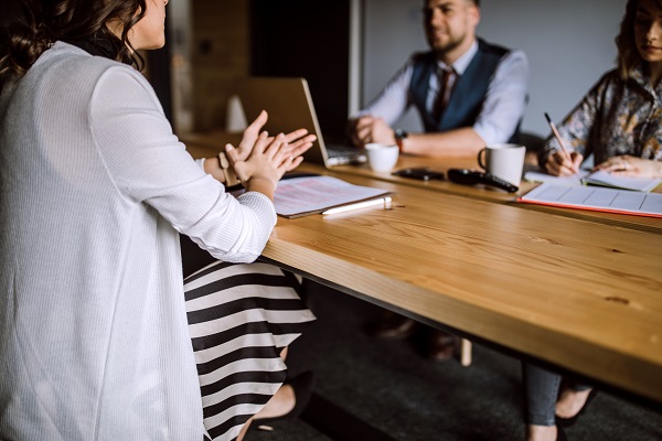 Man accompanied by two women sitting in board room