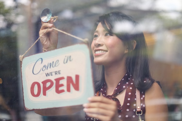 Business owner hanging an open sign at a cafe