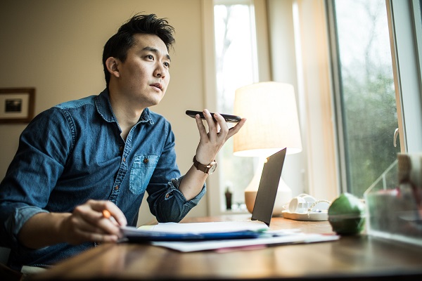 Man at desk at computer on cell phone