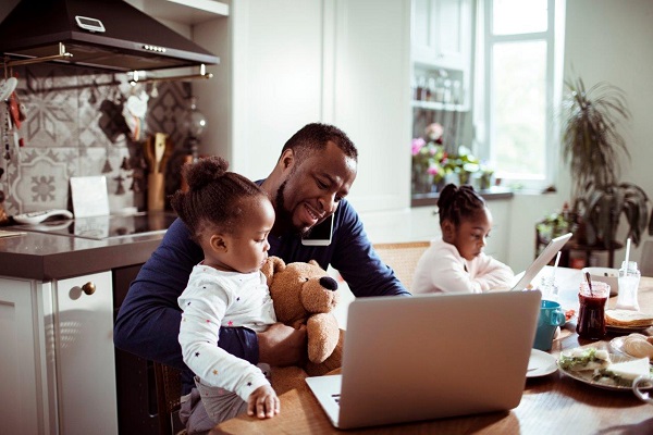 Family using a laptop in the morning, while father talks on phone