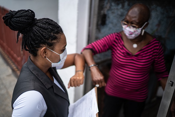 Surveyor greeting woman in doorway wearing face mask