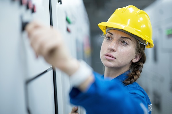 Woman in hardhat posting to bulletin board 