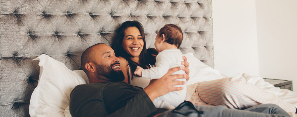 Mother, father, and baby in a bed happily together