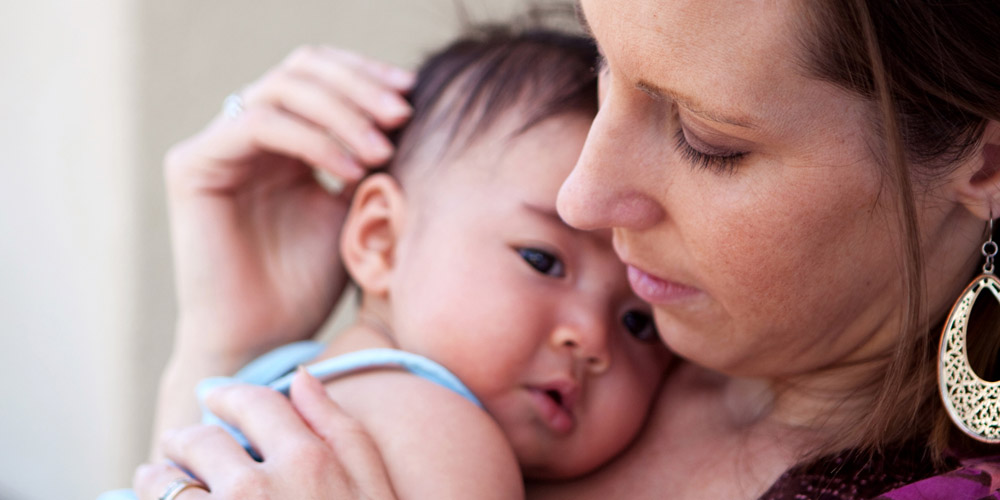 Woman snuggling her new baby while sitting down