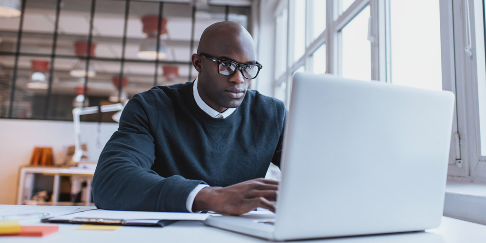 A man sitting at a laptop computer in a bright, modern office