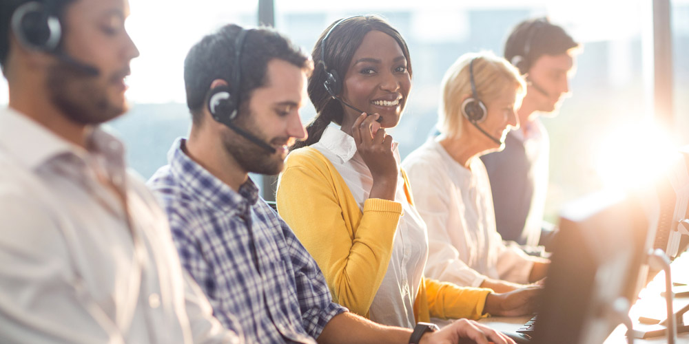 A smiling female African-American customer service agent using a headset to take a call