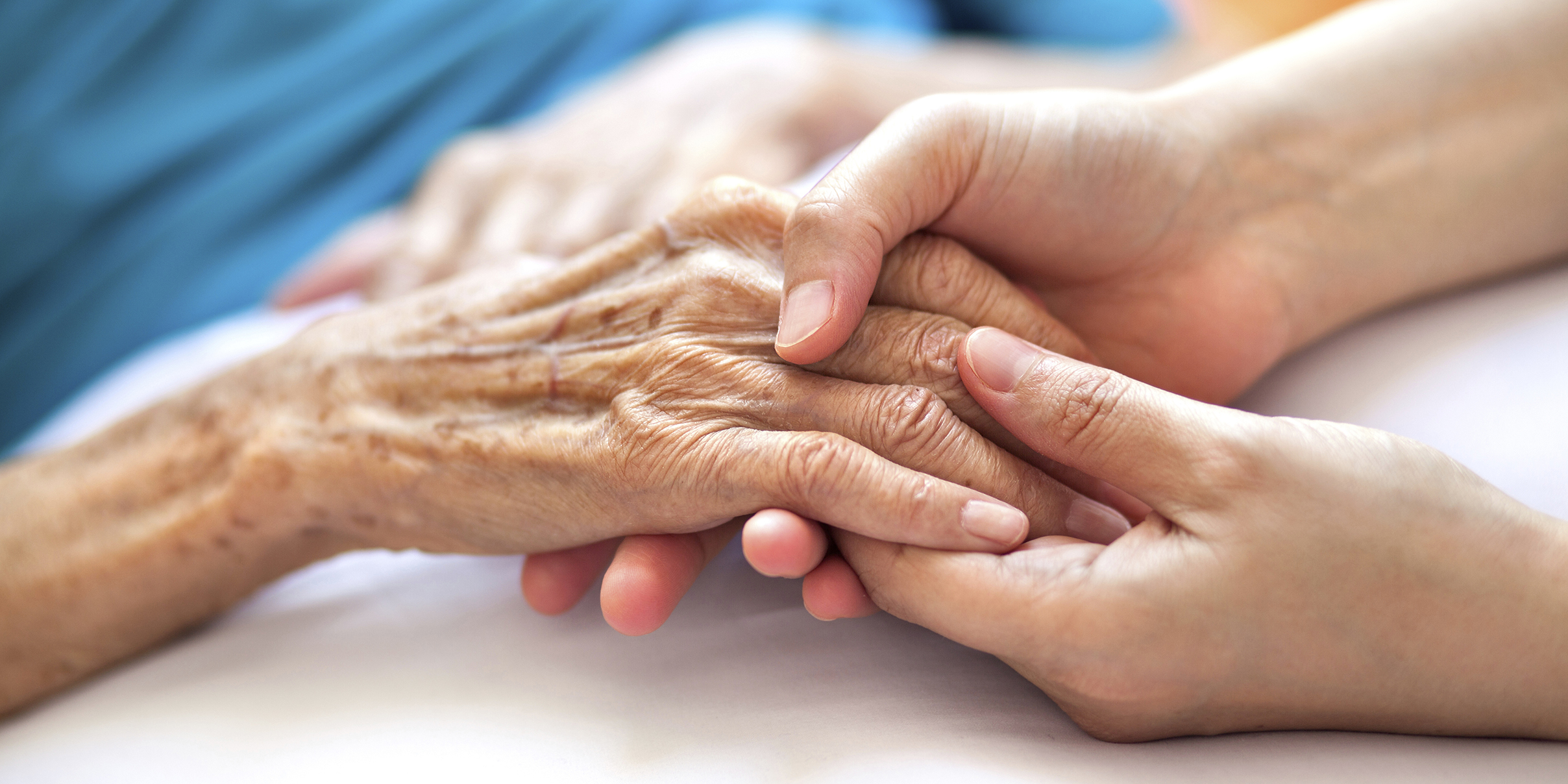 elderly hand being held by family member hand