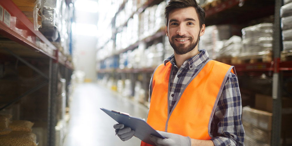 Man in warehouse holding clip board