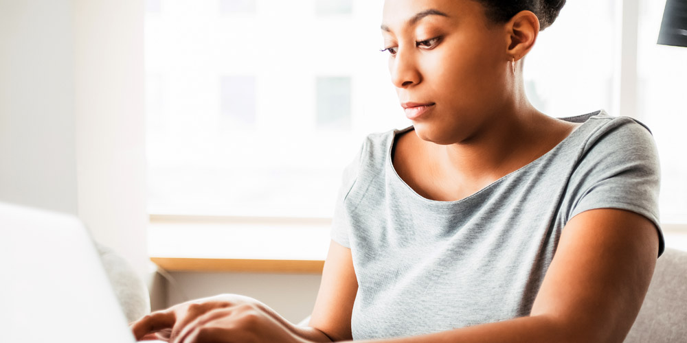 an African-American woman typing at a laptop computer