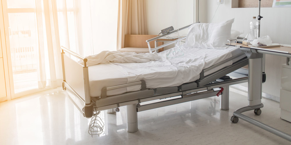 A modern, brightly lit hospital room with an empty bed