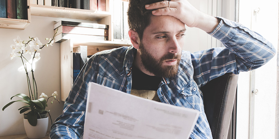 man with his hand to his head, reading mail