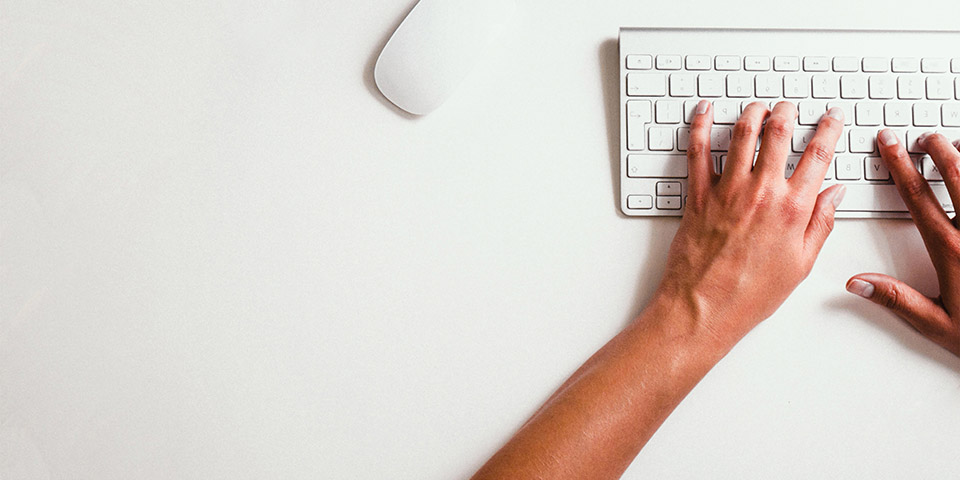 A woman's hands typing on a computer keyboard