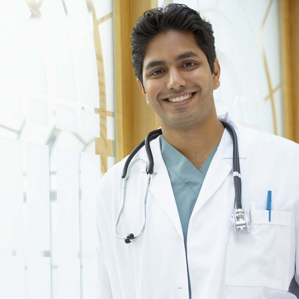 An Indian or South Asian doctor standing in front of a bright window