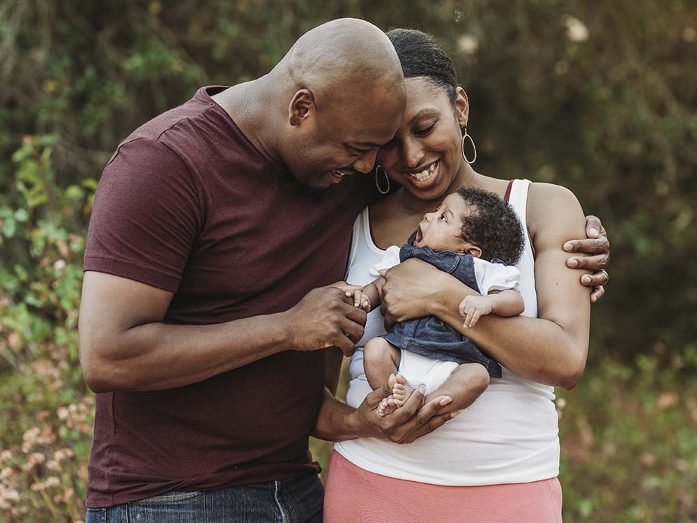 father and mother holding their new baby and smiling