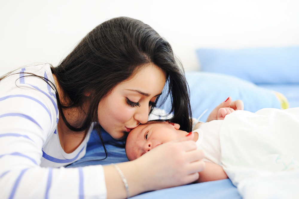 Smiling mother leaning in to kiss her baby