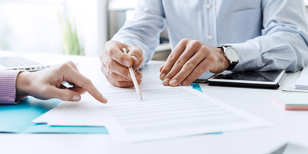 Two coworkers at a desk looking at a printed form together