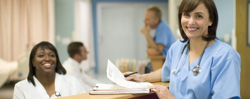 A smiling doctor and medical assistant or nurse at the desk of a medical office or hospital