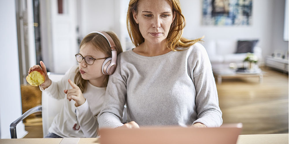 a woman working from home with her daughter next to her