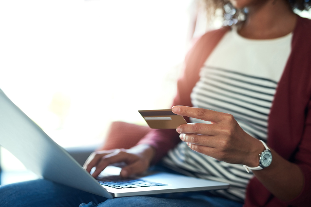 woman at a laptop holding a debit card