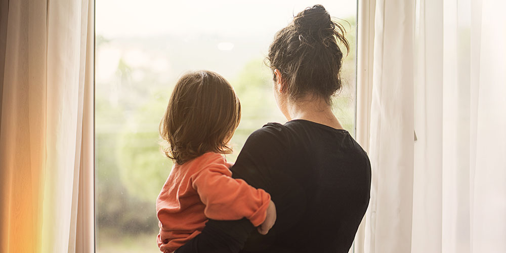 mother holding son looking out a window