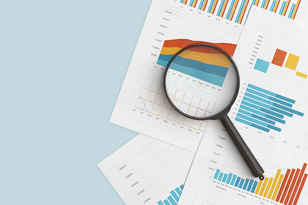 a graphic illustration of annual report printouts and a magnifying glass