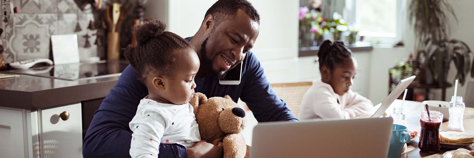 man with daughters on computers at their kitchen table