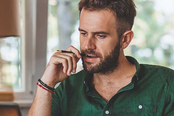 Man thinking with pen in mouth