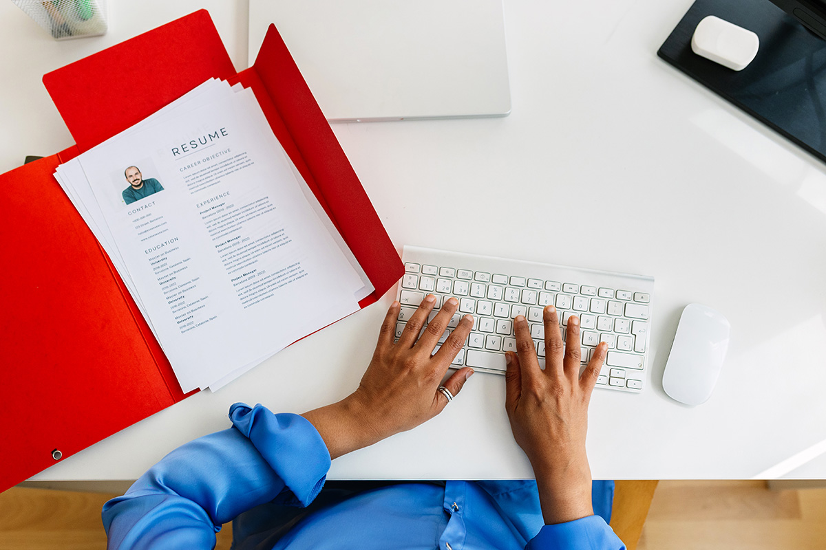 an overhead view of an HR manager's desk with a printed resume and hands on a keyboard
