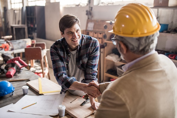 Two men shaking hands over table