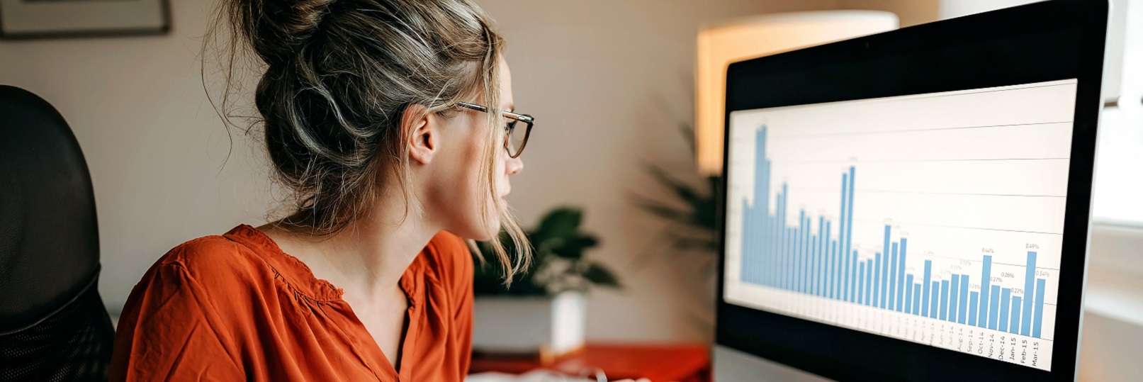 woman at desktop computer with charts and graphs on screen