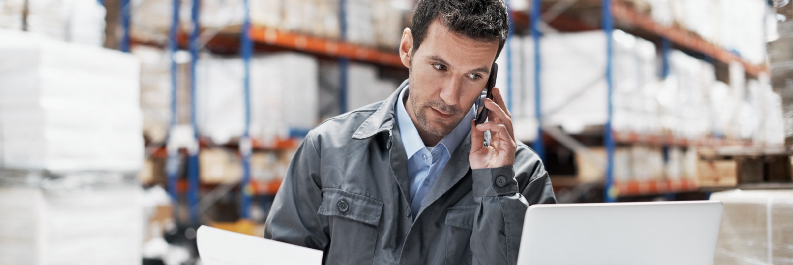 man in warehouse on phone at computer