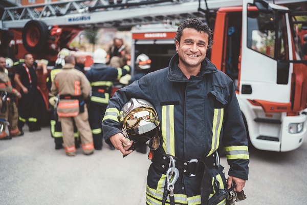 Firefighter smiling while holding helmet under arm 