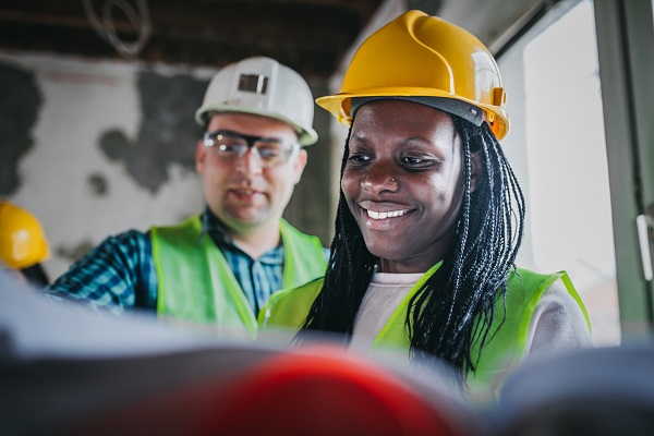 Woman in hard hat smiling looking at plans