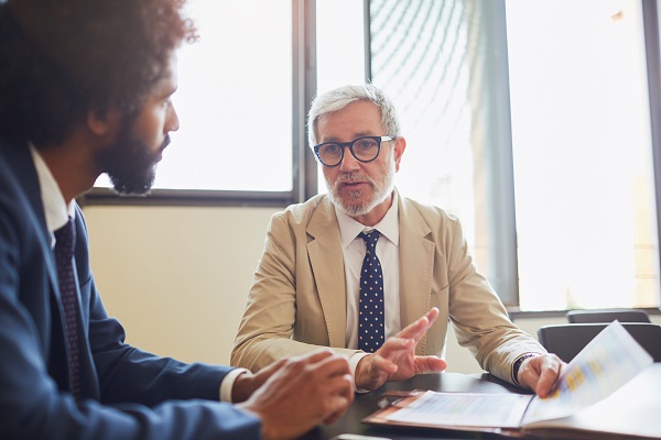 Two men sitting at table discussing paperwork