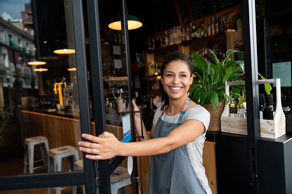 Woman holding door open to restaurant