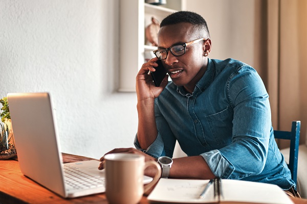 Man talking on a cell phone while working at a laptop