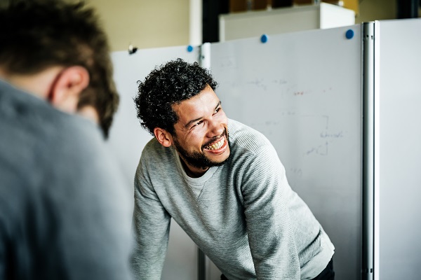 Man smiling while leaning over desk