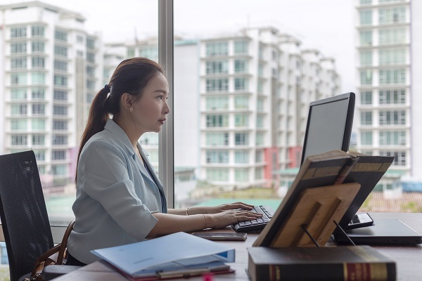 Female typing on keyboard, preparing legal document and getting reference from law books